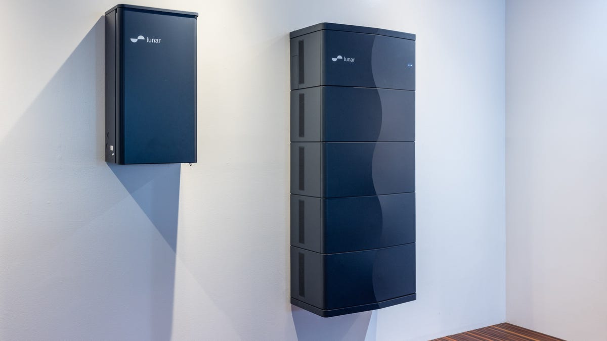 A Lunar Energy battery, a modular system with an S-curve detail down the front panels, is mounted on a white wall