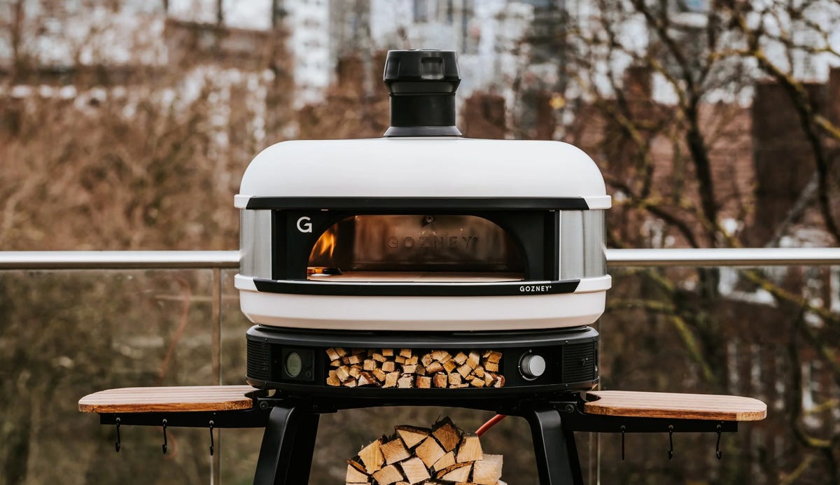 Large circular pizza oven with stacks of wood beneath it 