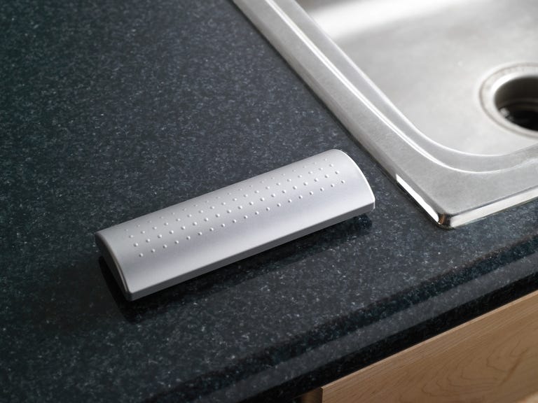 A brushed silver remote contol on a granite countertop.