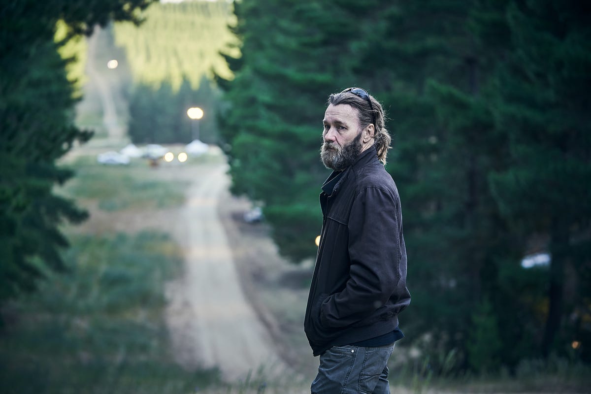 Joel Edgerton standing on a dirt road in a forest