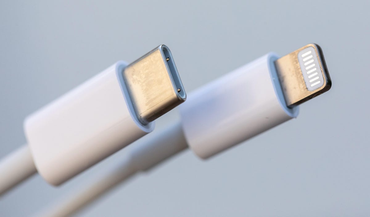 A close-up view of the USB-C and Lightning connectors at the ends of an Apple charging cable.