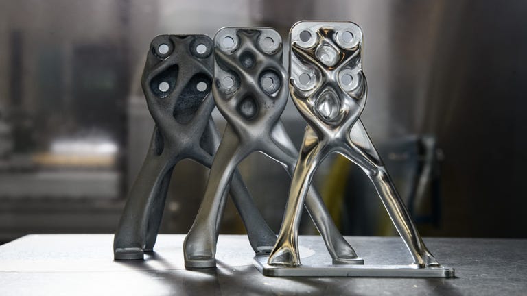 Three metal parts look like little sculptures with two legs and a multiple holes around the top. They were designed with AI assistance for a balloon-born Excite telescope.