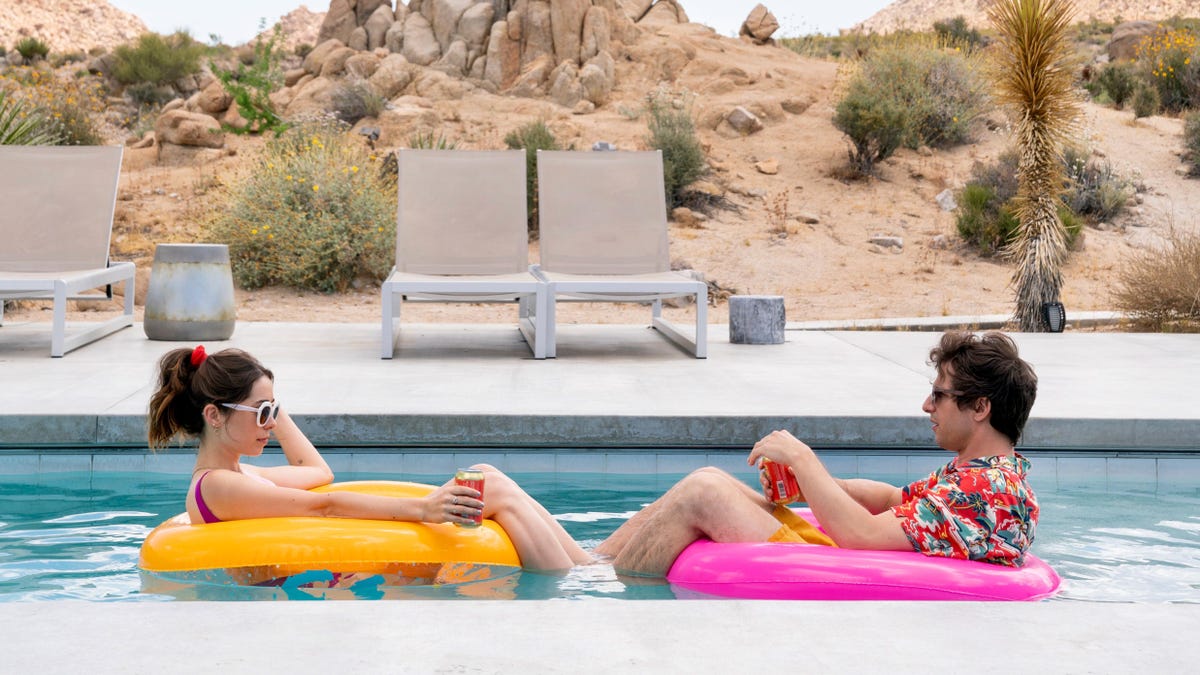 Cristin Milioti och Andy Samberg sitter i en gul respektive rosa poolpojke, vända mot varandra och dricker öl