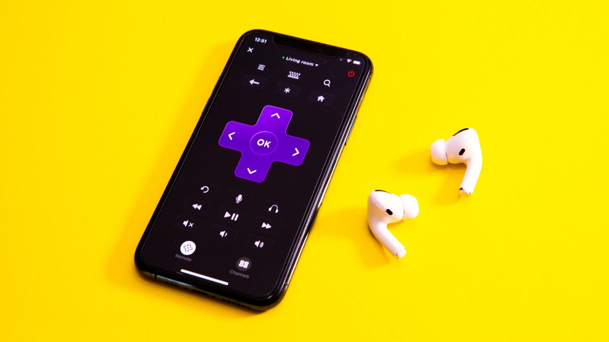 Roku app on a phone next to wireless earbuds