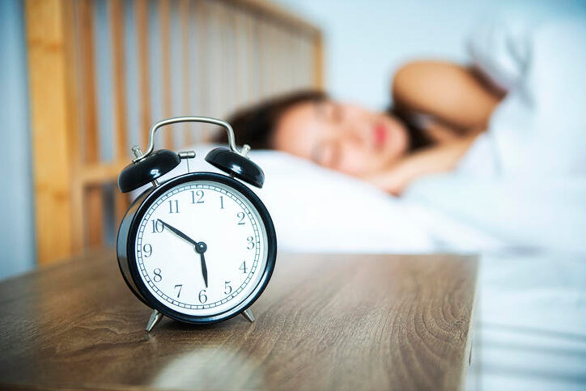 Alarm clock next to a woman sleeping. 