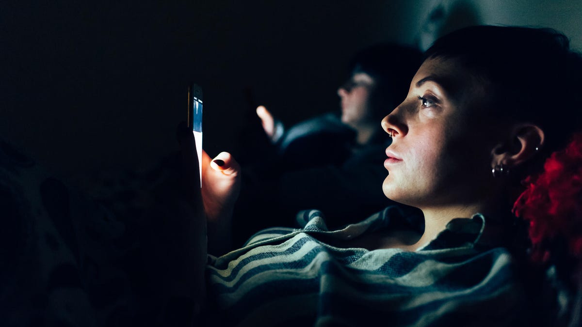 Man sitting on edge of bed in a dark room