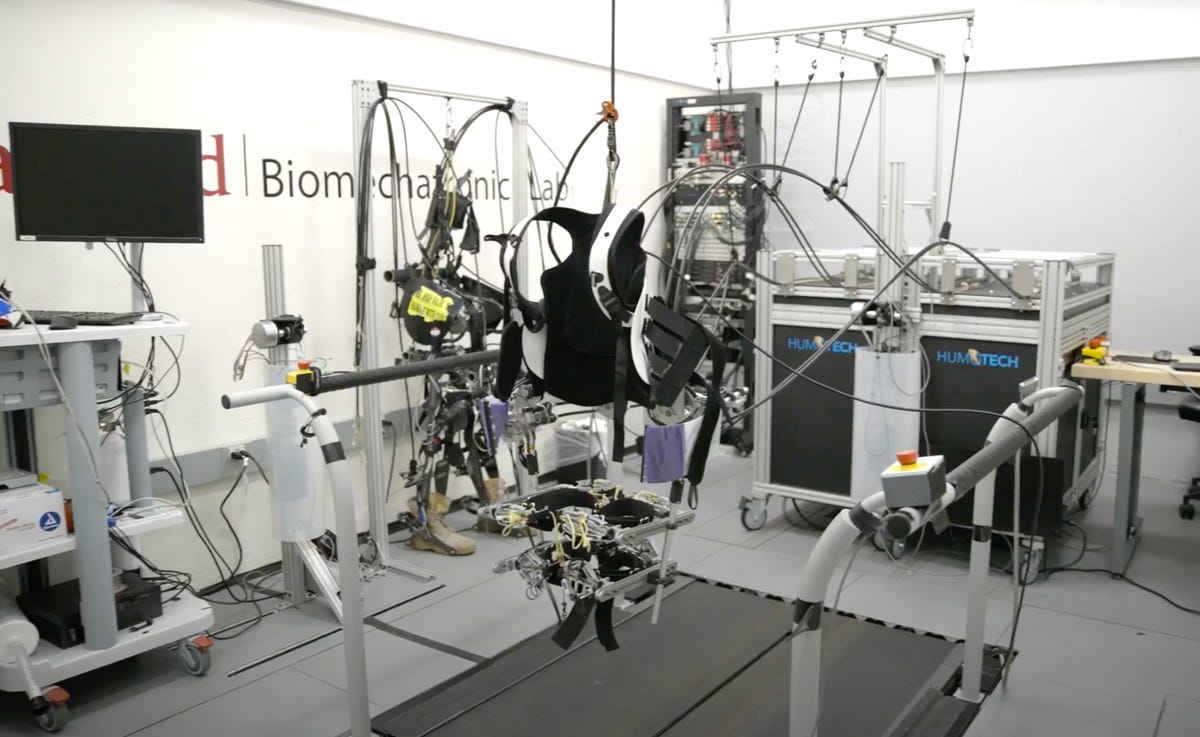 An image of an empty chest harness and leg braces hanging over a treadmill inside a lab that allows researchers to test walking in a controlled environment.