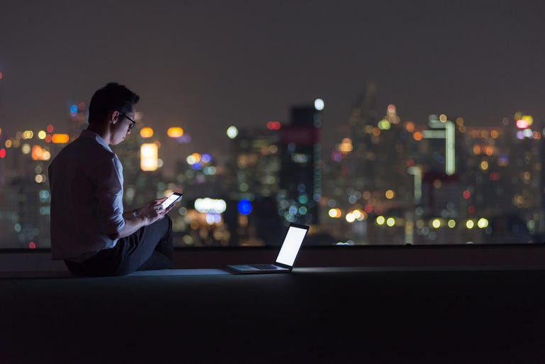 Business man using  smartphone and laptop on rooftop