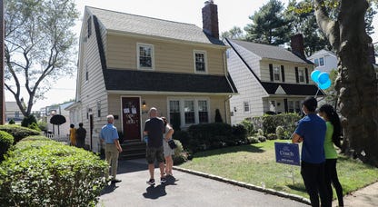 Prospective buyers outside a small two-floor house for sale