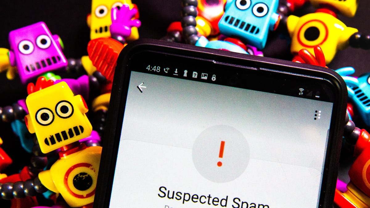 A phone screen with a "Suspected Spam" warning, with little toy robots in the background