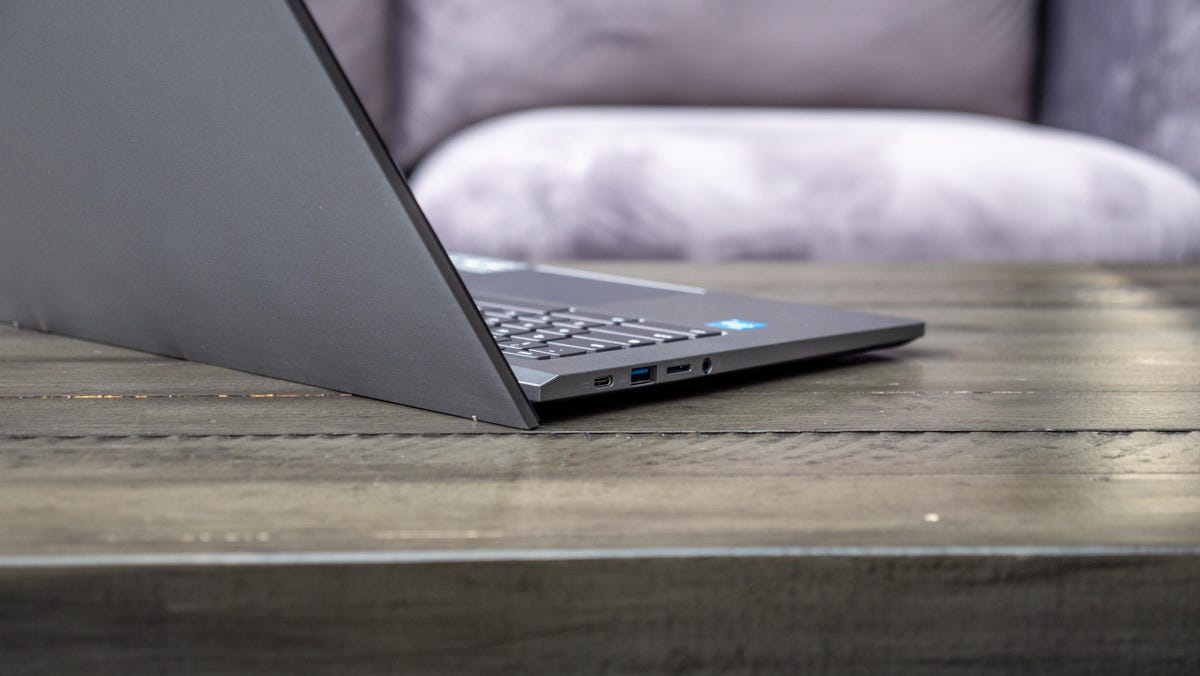 Acer Chromebook Plus 514 aberto e voltado para trás em uma mesa de madeira em frente a um sofá cinza claro.