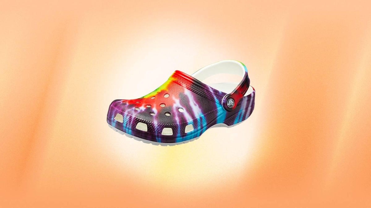 A tie-dyed Crocs clog against an orange background.