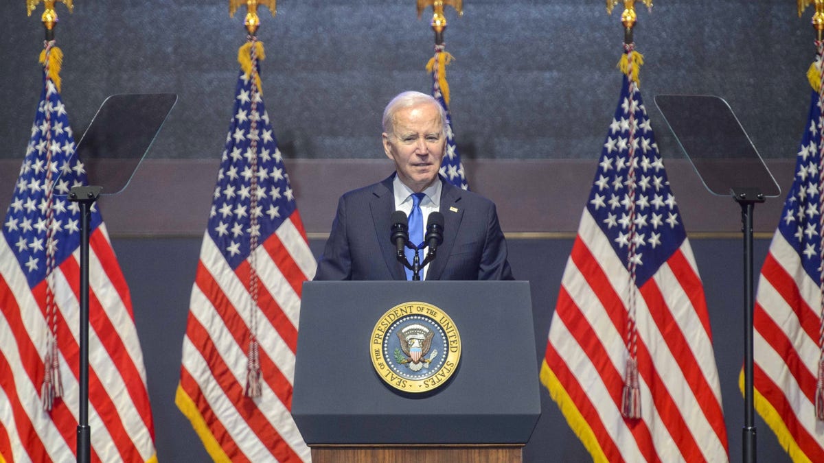 president joe biden stands at podium with American flags in background at National Prayer Breakfast 2023