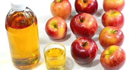 A bottle of apple cider vinegar with nine apples