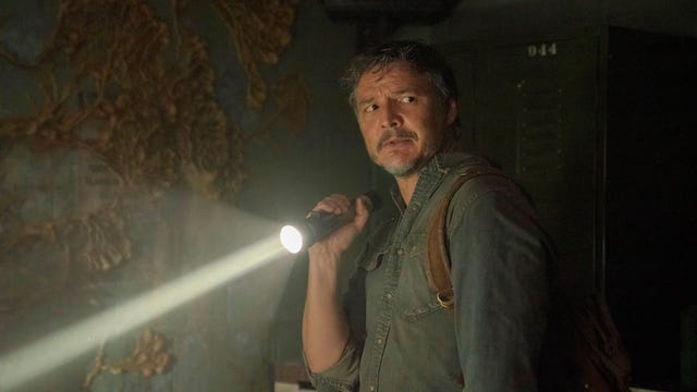 Pedro Pascal holding a torch in a dank room