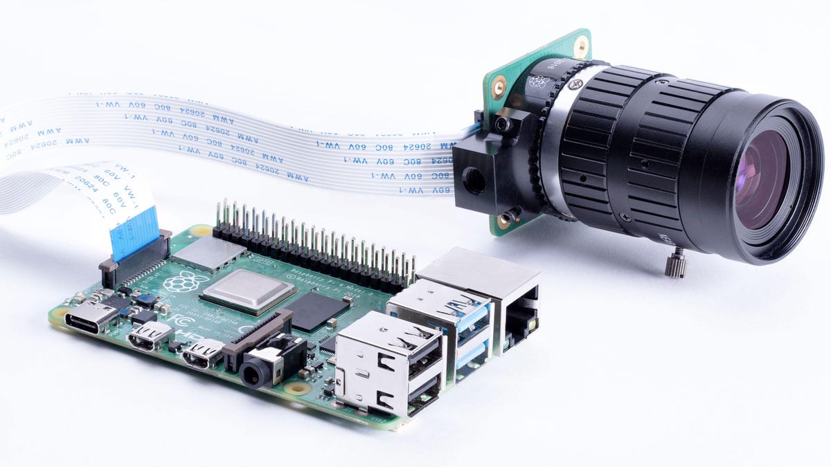 The Raspberry Pi High Quality Camera is shown here with a separate $50 lens attached and a ribbon cable connection to a Raspberry Pi computer.