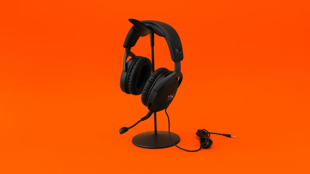 HyperX Cloud Stinger 2 hanging on a headset stand on an orange background