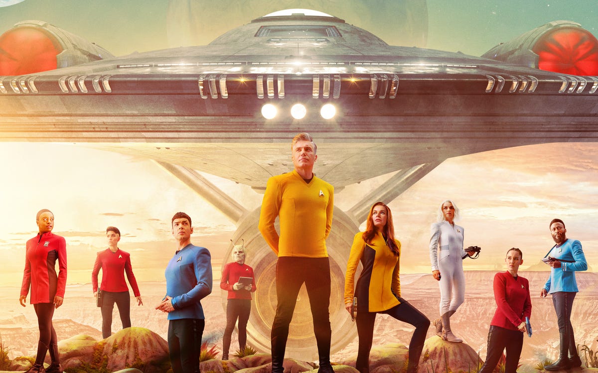 The Enterprise crew line up in front of their starship.