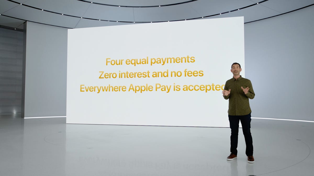 Corey Fugman in front of a screen with the message "Four equal payments, Zero interest and no fees, Everywhere Apple Pay is accepted" on it