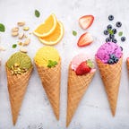 Above view of ice cream cones with various fruits spilling out of the cones.