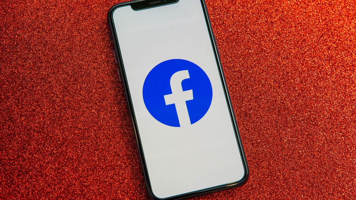Facebook logo on smartphone in front of red background 