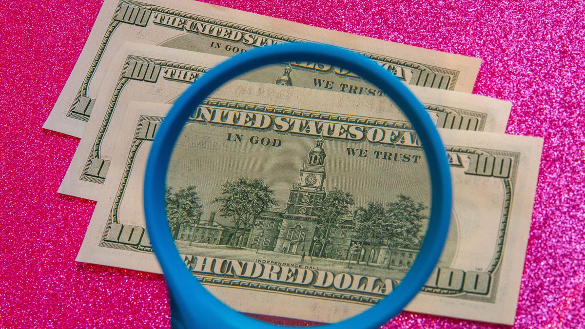 examining cash with a magnifying glass