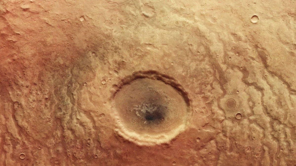An eyeball-like crater in the Aonia Terra region of Mars sits against a reddish Martian landscape.