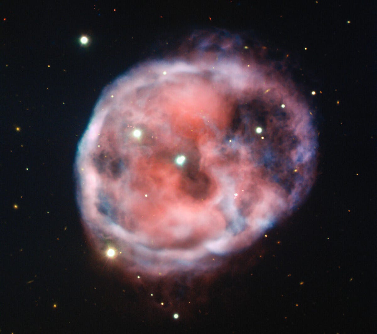 Blobby looking nebula looks a little like a cute round skull with two eyes and a mouth against the backdrop of starry space.