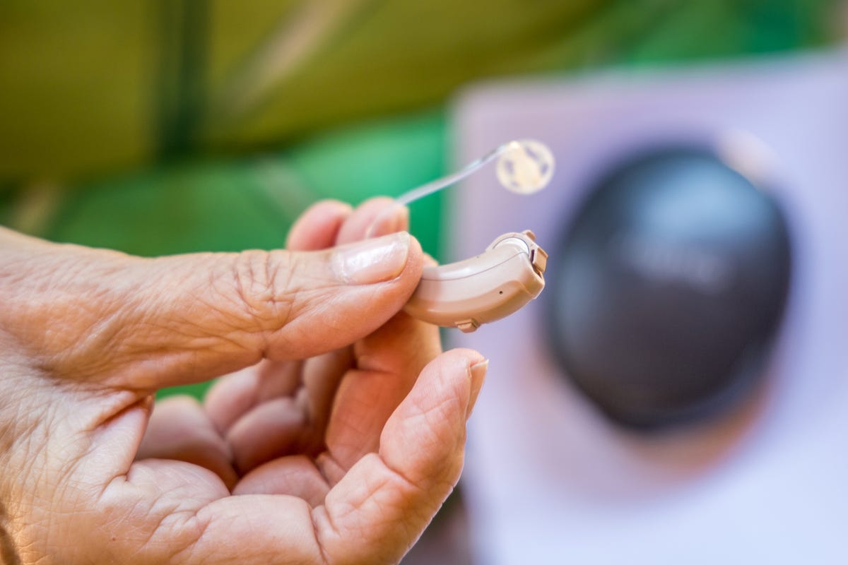 Close-up of hands holding a modern hearing aid