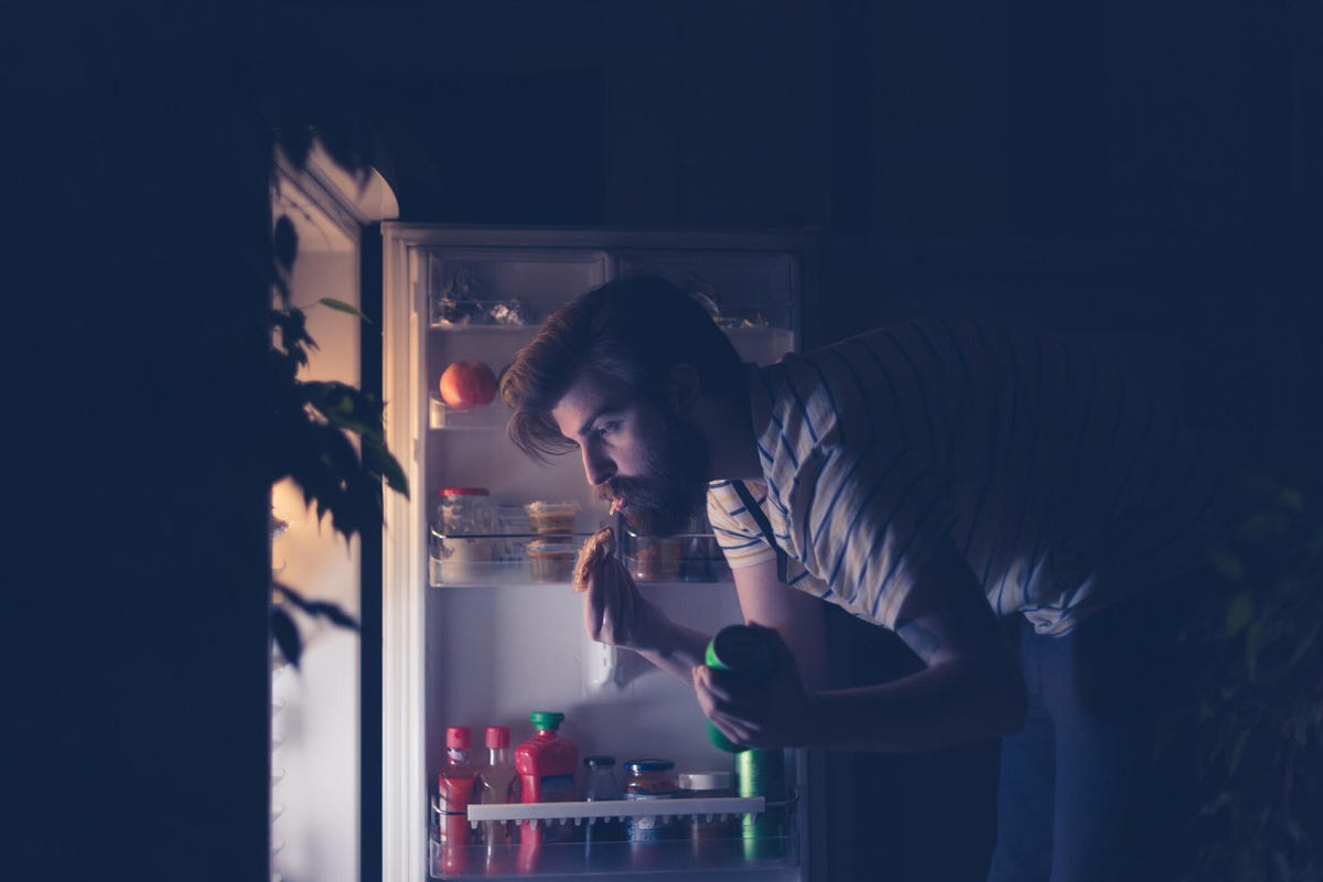 Man having a late night snack in front of an open refrigerator
