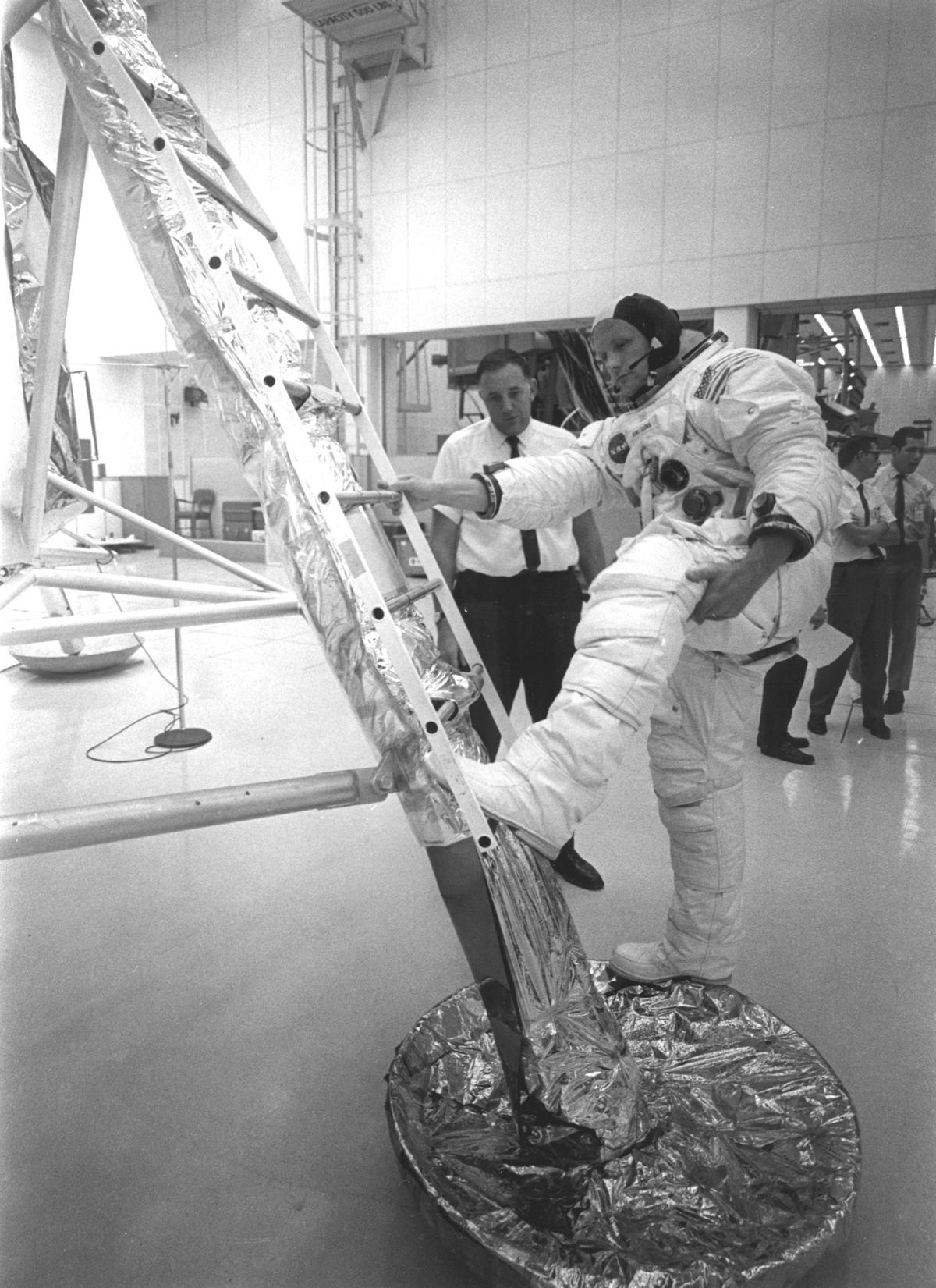 Dressed in his EVA spacesuit, Neil Armstrong practices climbing up onto the ladder of the LEM.