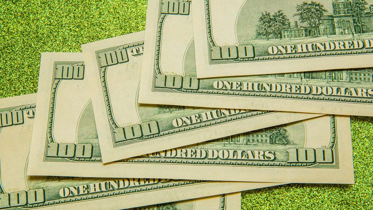 $100 bills scattered against a green background