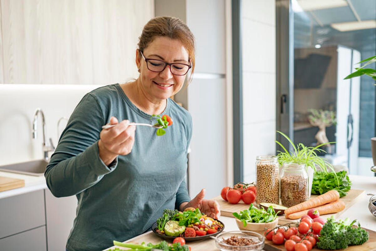 Woman eating a salad in her kitchen.