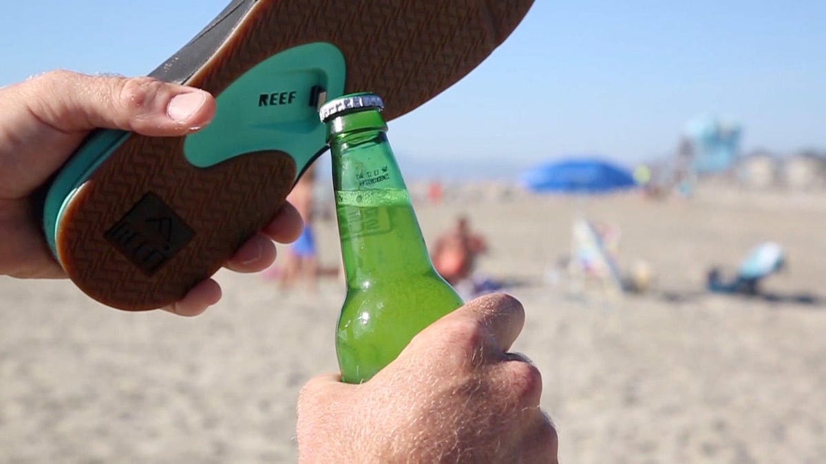 prying off a bottle cap with a sandal on the beach