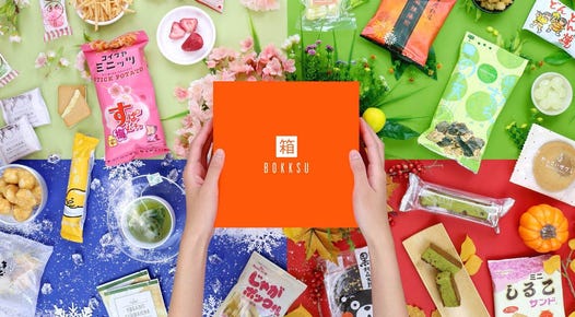 The Bokksu subscription box and a lot of snacks are displayed against a colorful background.