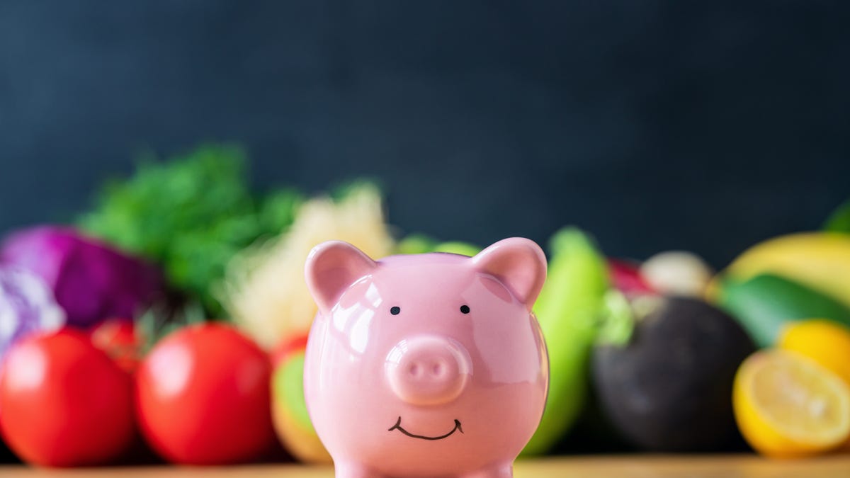 a piggy bank on a counter surrounded by fruits and vegetables