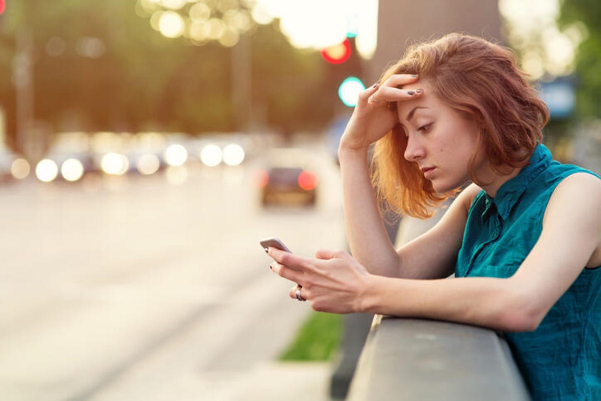 Stressed woman checking her phone while outside.