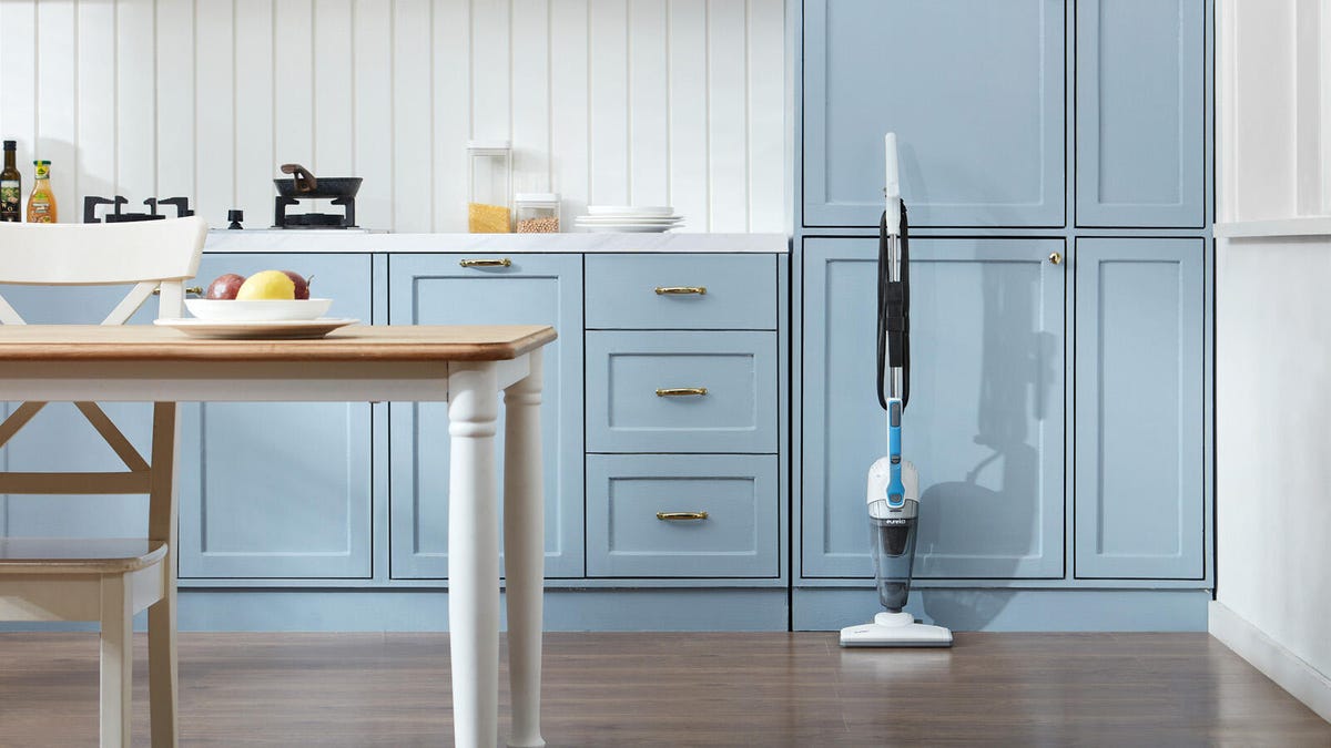 The Eureka NES100 3-in1 vacuum is standing inside of a clean kitchen.