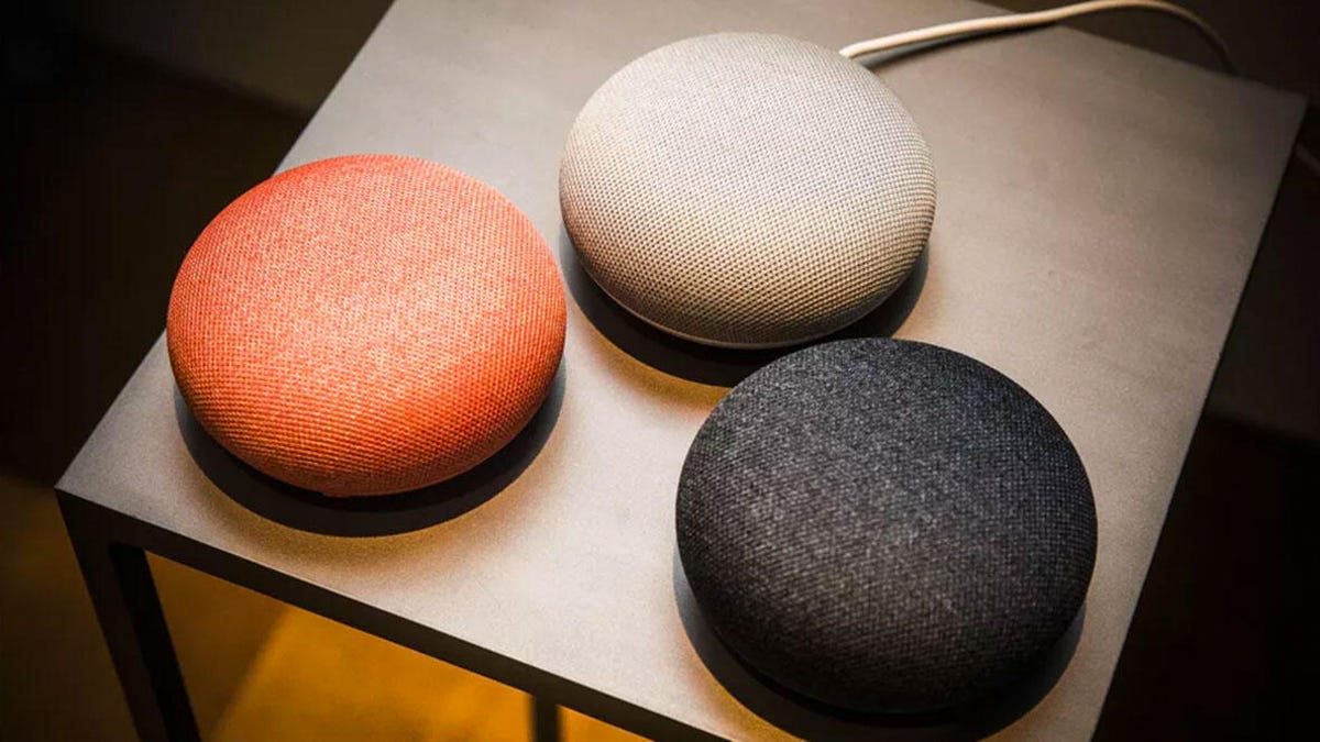 A trio of Google Home Mini speakers of different colors.