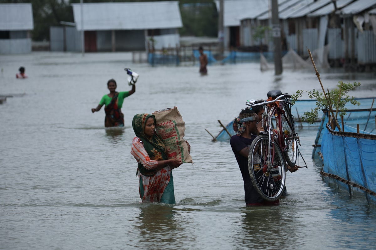 People in Koyra, Bangladesh, wade through flood waters after Cyclone Yaas