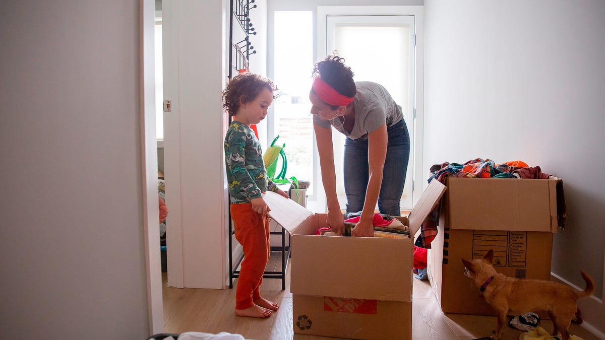 A mother and child unpack a large cardboard box