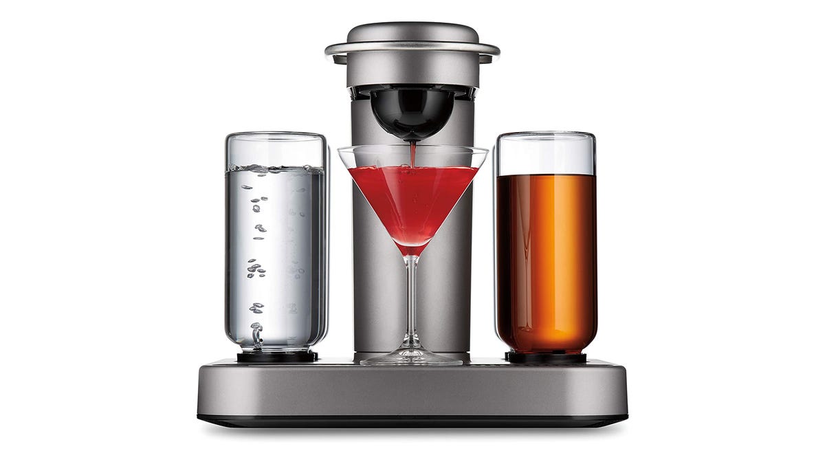 A mixing machine shows spirits in containers as a cocktail glass is filled with a mixed drink.