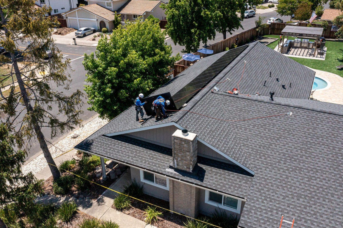 Workers install solar panels on a home in California.
