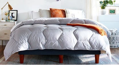 A bed made with a Layla Down Alternative comforter with a nightstand next to it.