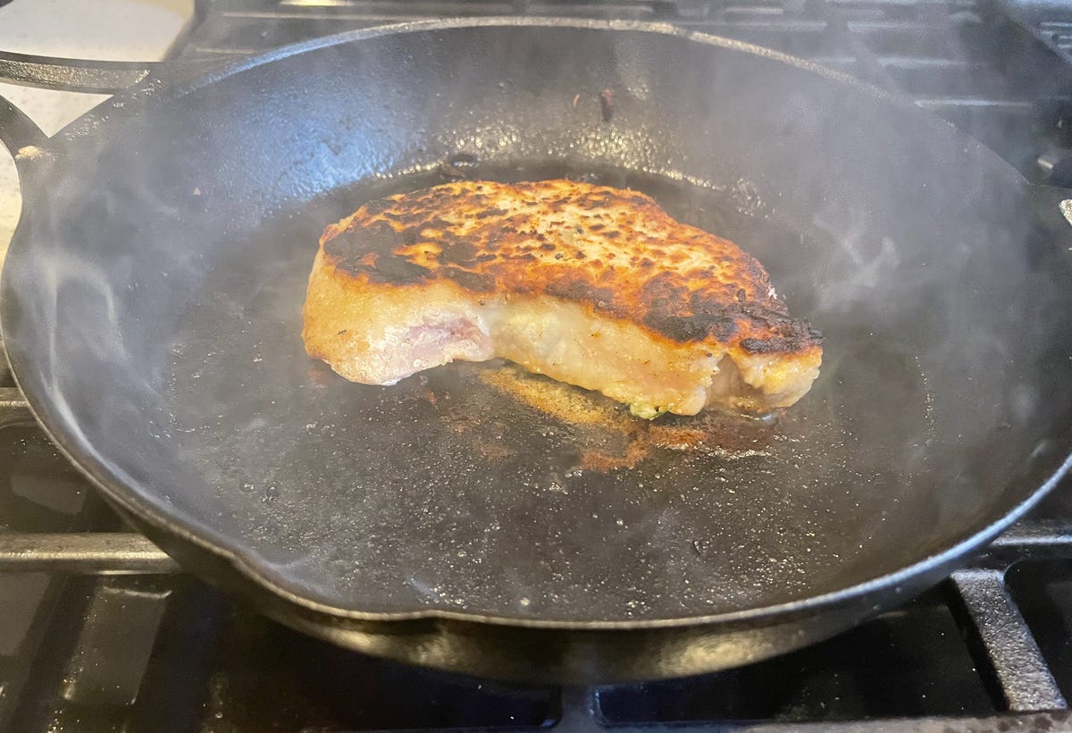 potongan daging babi dalam wajan besi cor