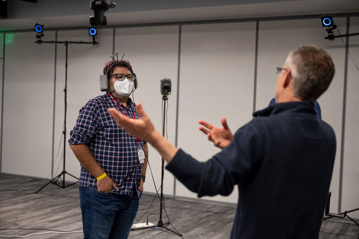 A man wearing a mask and headphones in a testing room with speakers