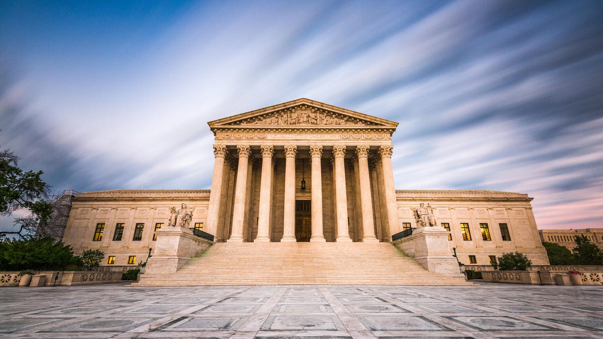 The US Supreme Court building against a blurred cloudy sky.