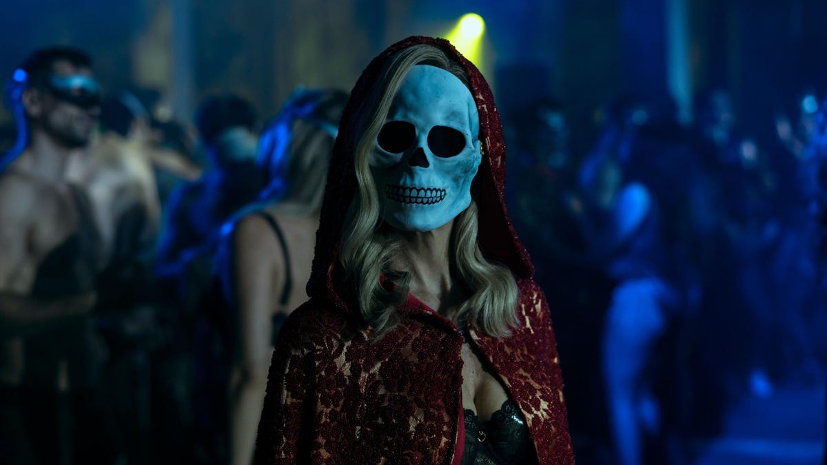 woman wears red lace hooded cloak and skeleton mask