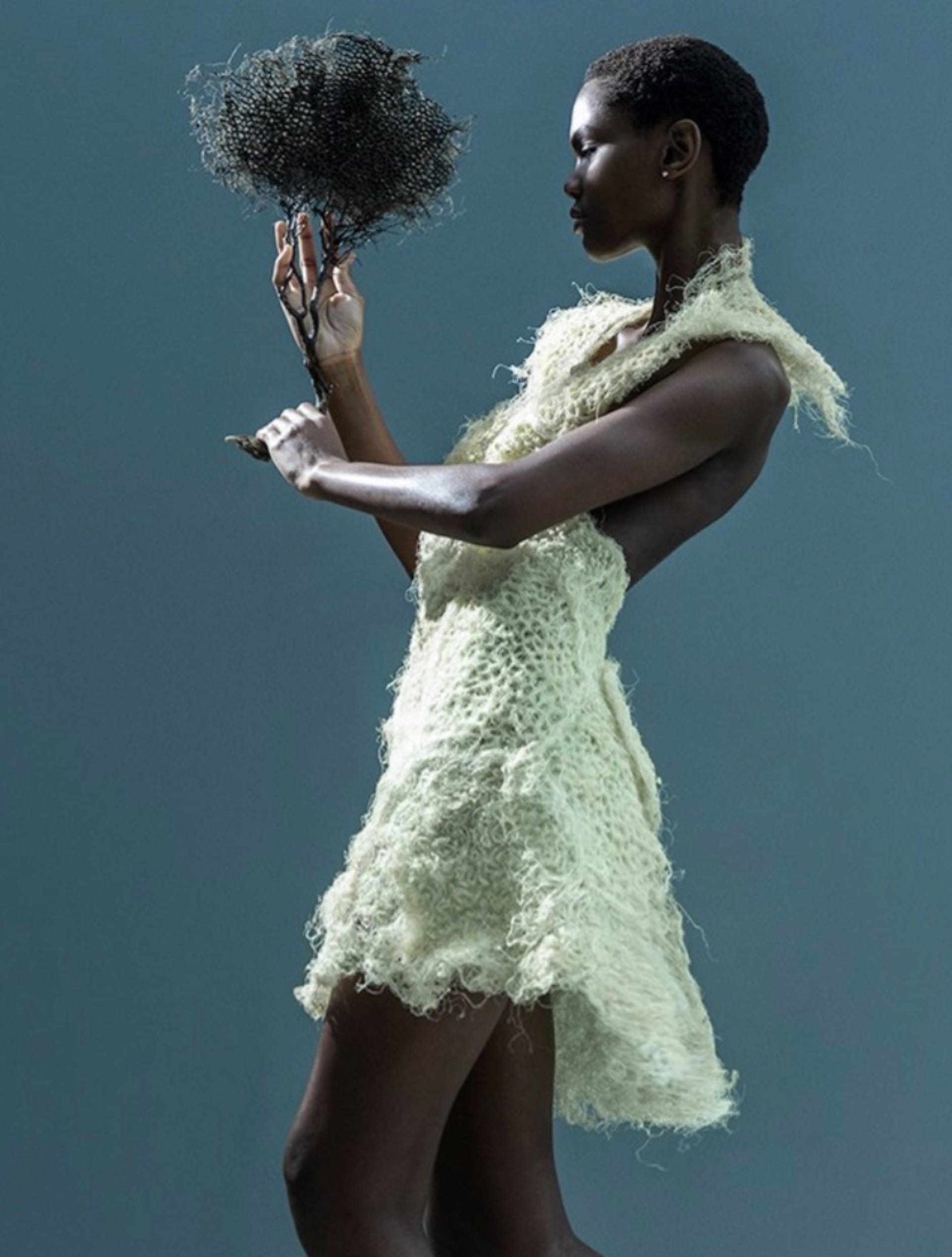 A model wears a short dress made from grass root and holds a ball of root dyed dark