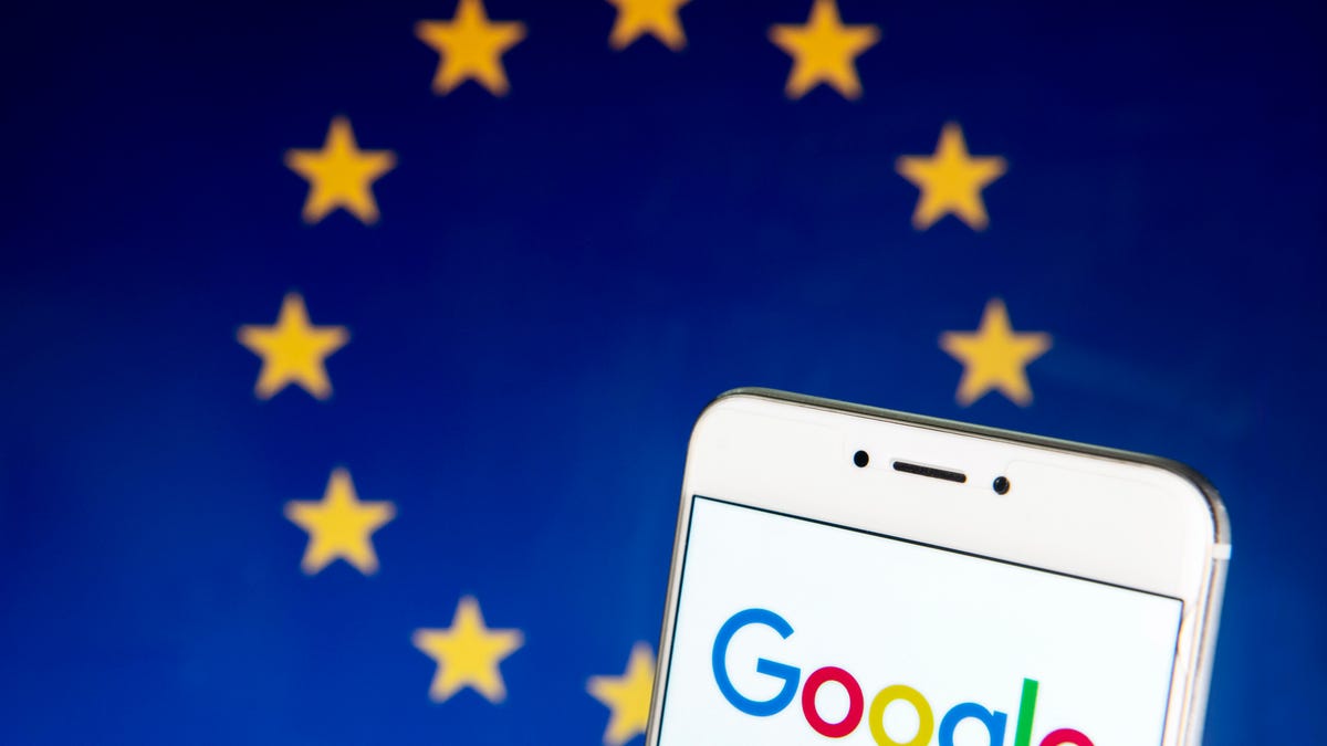 Google logo on phone screen, with EU flag as backdrop